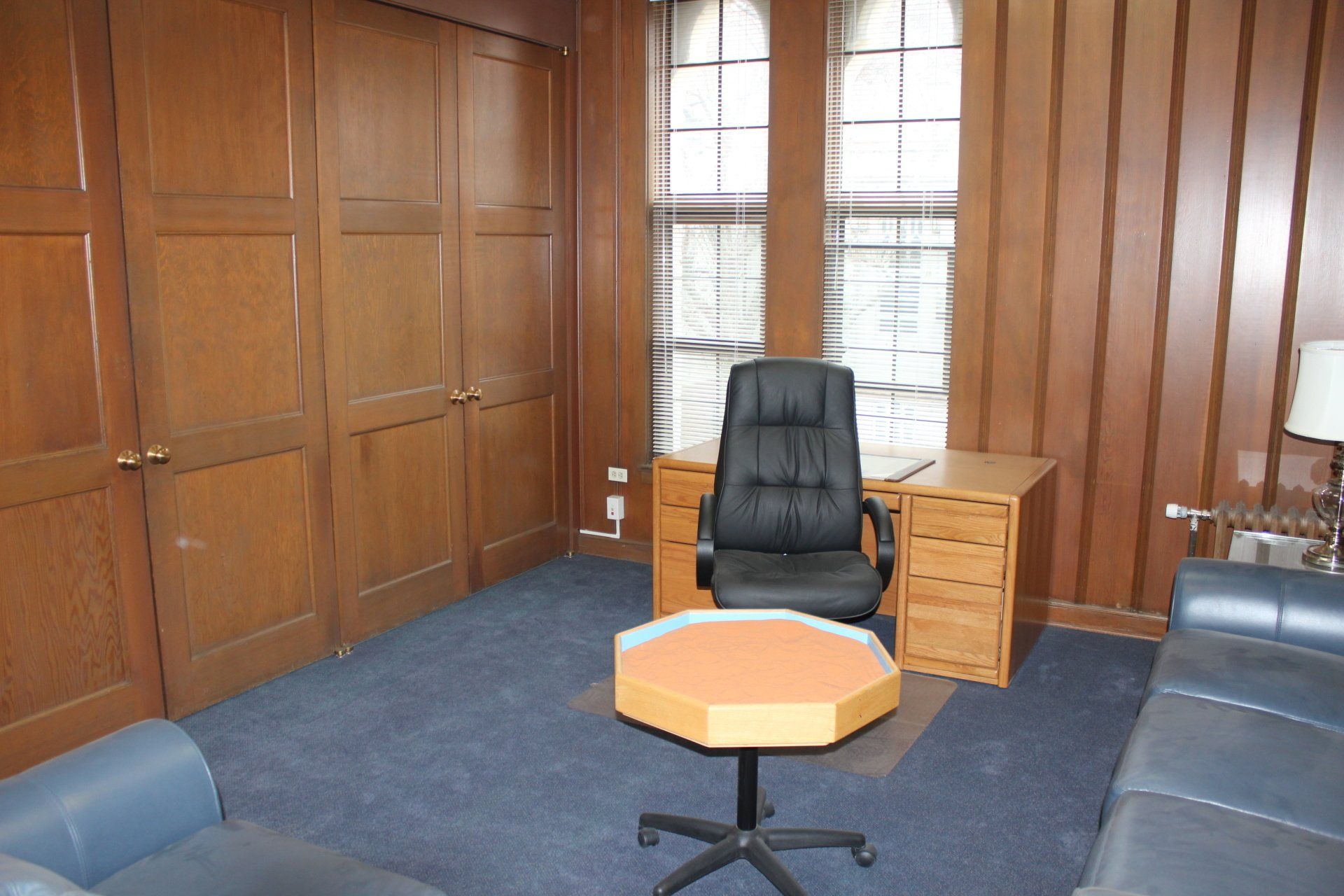A living room with a couch a desk and a chair