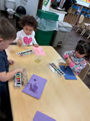 A group of children are sitting at a table playing with watercolors.
