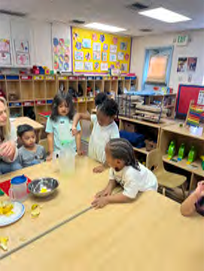 A group of children are sitting around a table in a classroom.