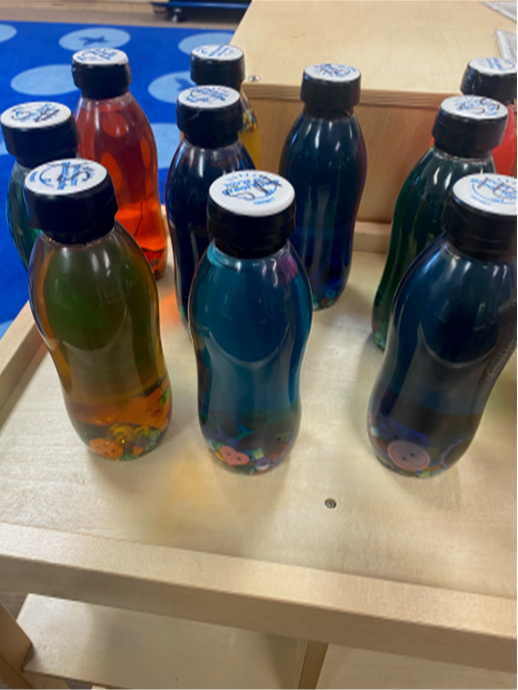 A bunch of bottles are lined up on a wooden table
