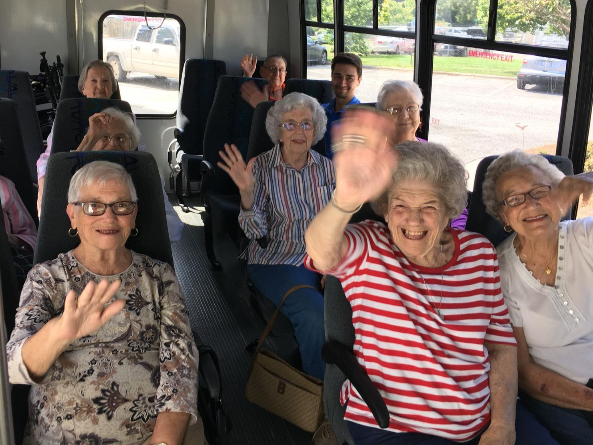Group of people waving from inside a bus.  Independent senior living community near New Bern, NC.