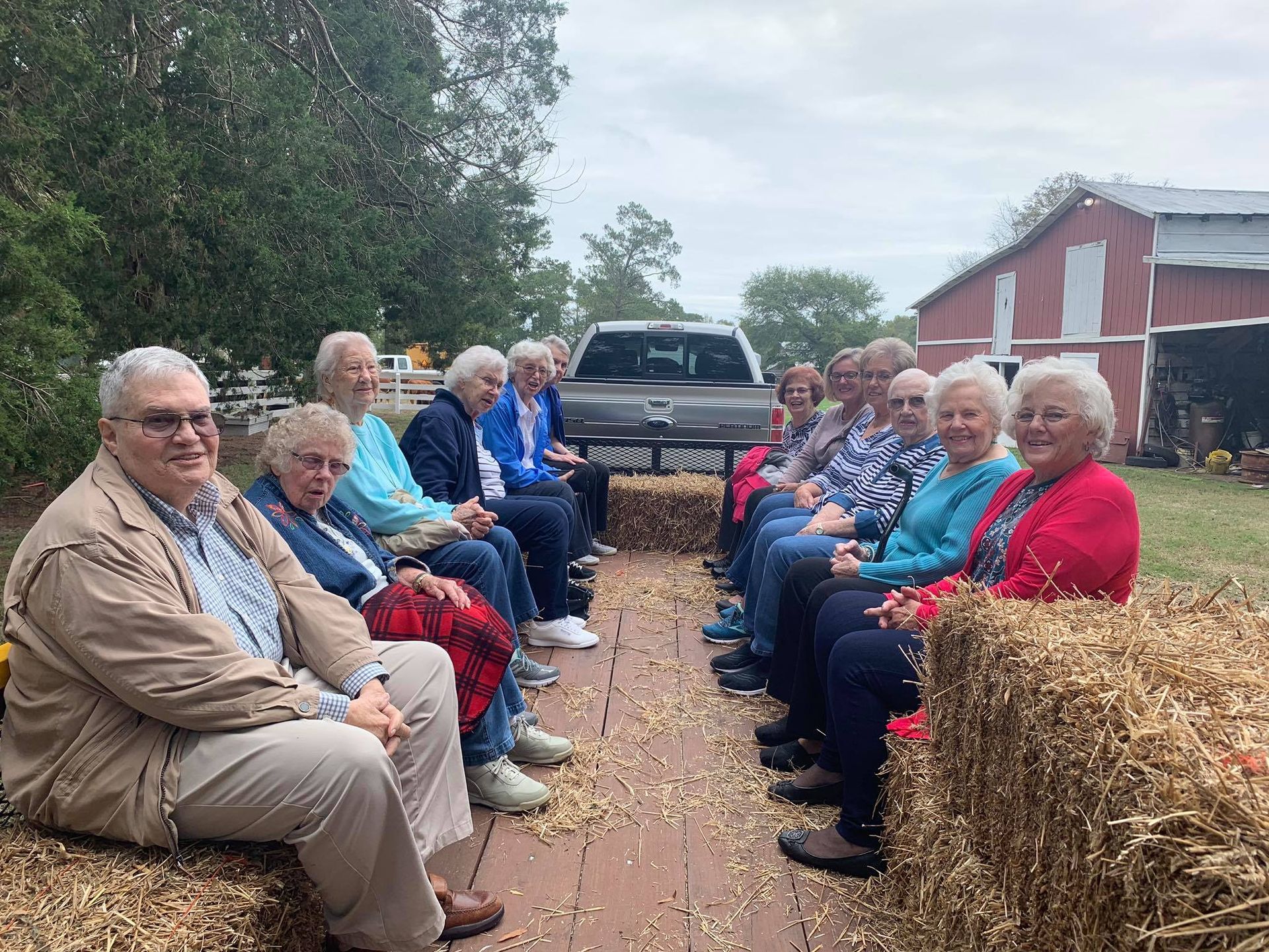 A group of people are sitting on bales of hay.