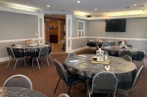 A large room with tables and chairs and a flat screen tv.