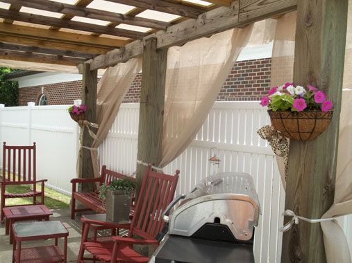 A patio with a grill and chairs under a pergola