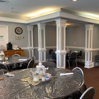 A diner interior with round tables covered in plastic. Decorative columns, neutral colors, and a coffee station.