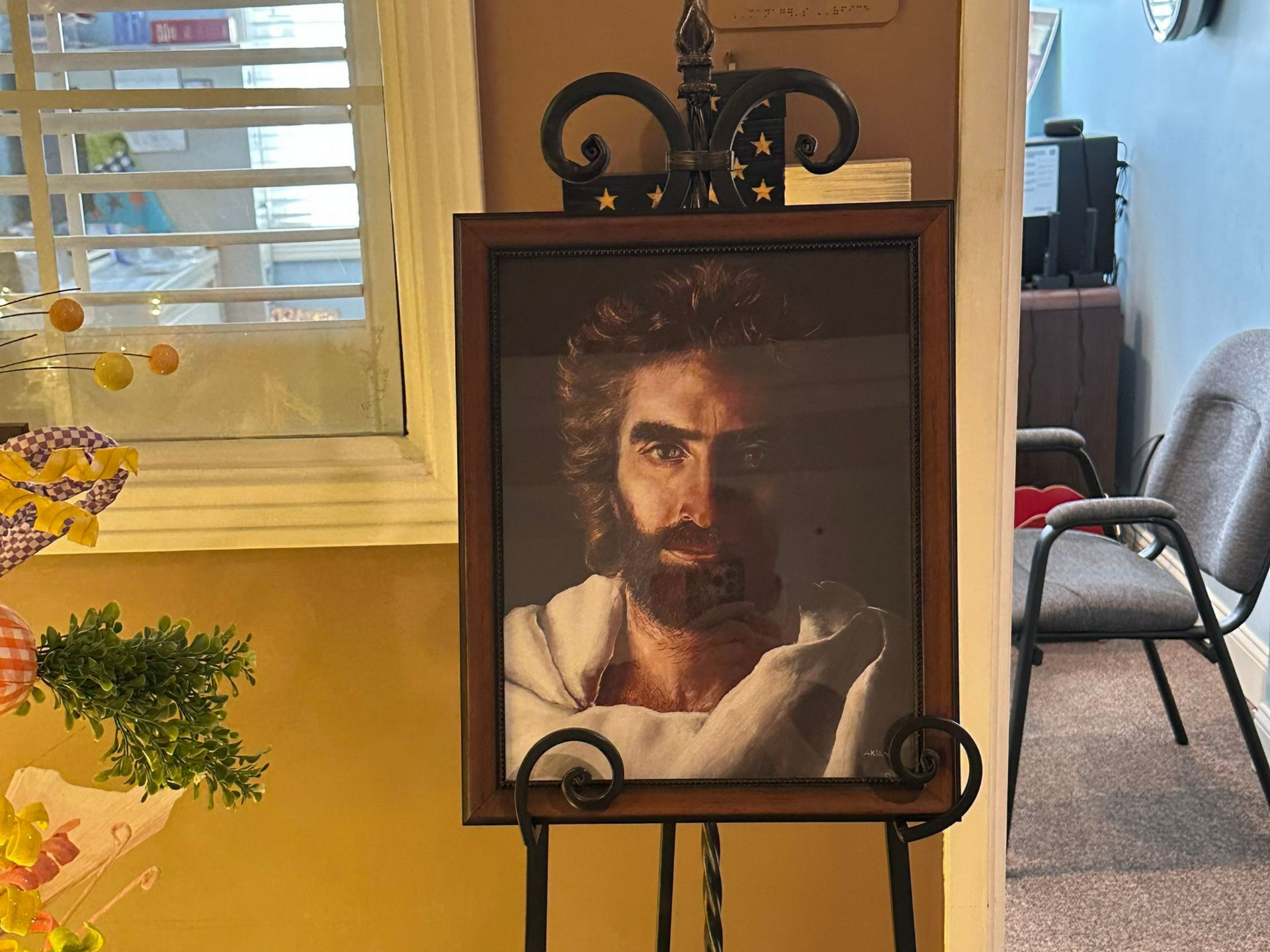 Painting of Jesus on an easel; interior hallway with manager's office sign and window with blinds. Senior retirement community near Goldsboro NC.