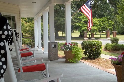 A porch with rocking chairs and an american flag
