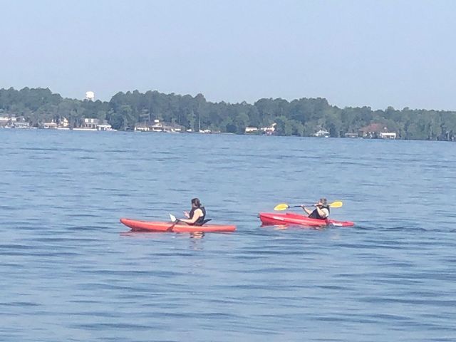 Two people are in red kayaks on a lake