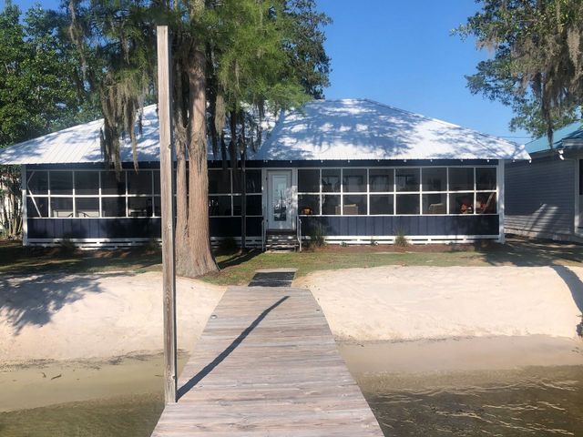 There is a dock in front of a house on the water.