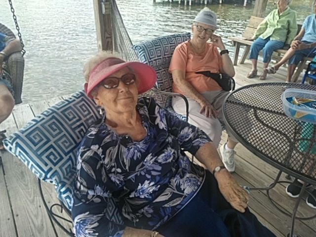 A group of older women are sitting at a table by the water.