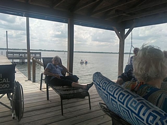 A group of people are sitting on a dock overlooking a lake.