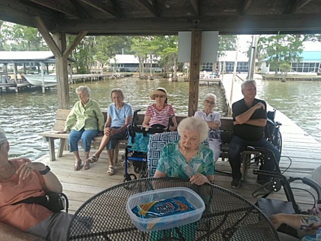 A group of people are sitting at a table in front of a body of water.