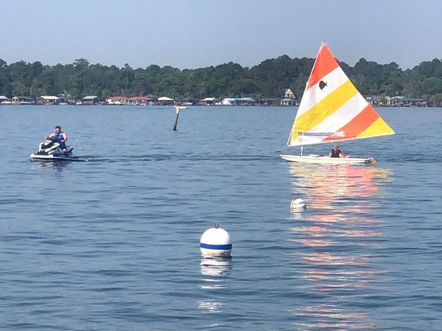 A man on a jet ski next to a sailboat