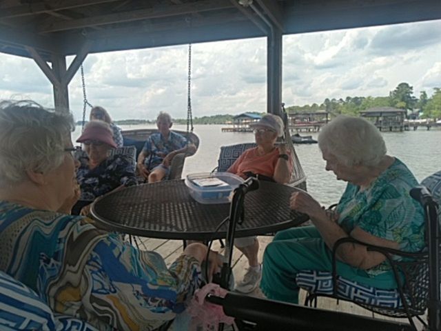 A group of elderly people are sitting at a table by the water.