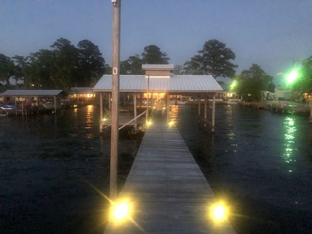 A dock with lights on it and a house in the background
