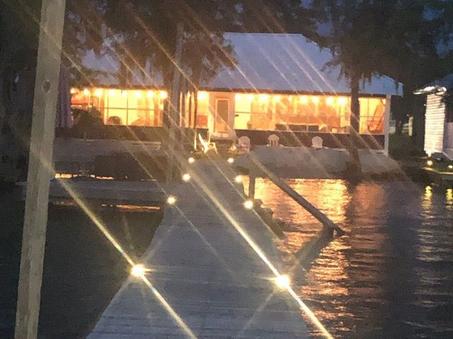 A house is lit up at night with a dock in the foreground