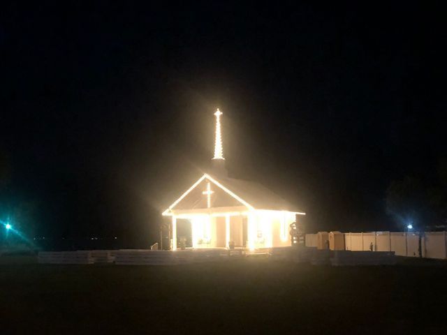 A church is lit up at night with a cross on top