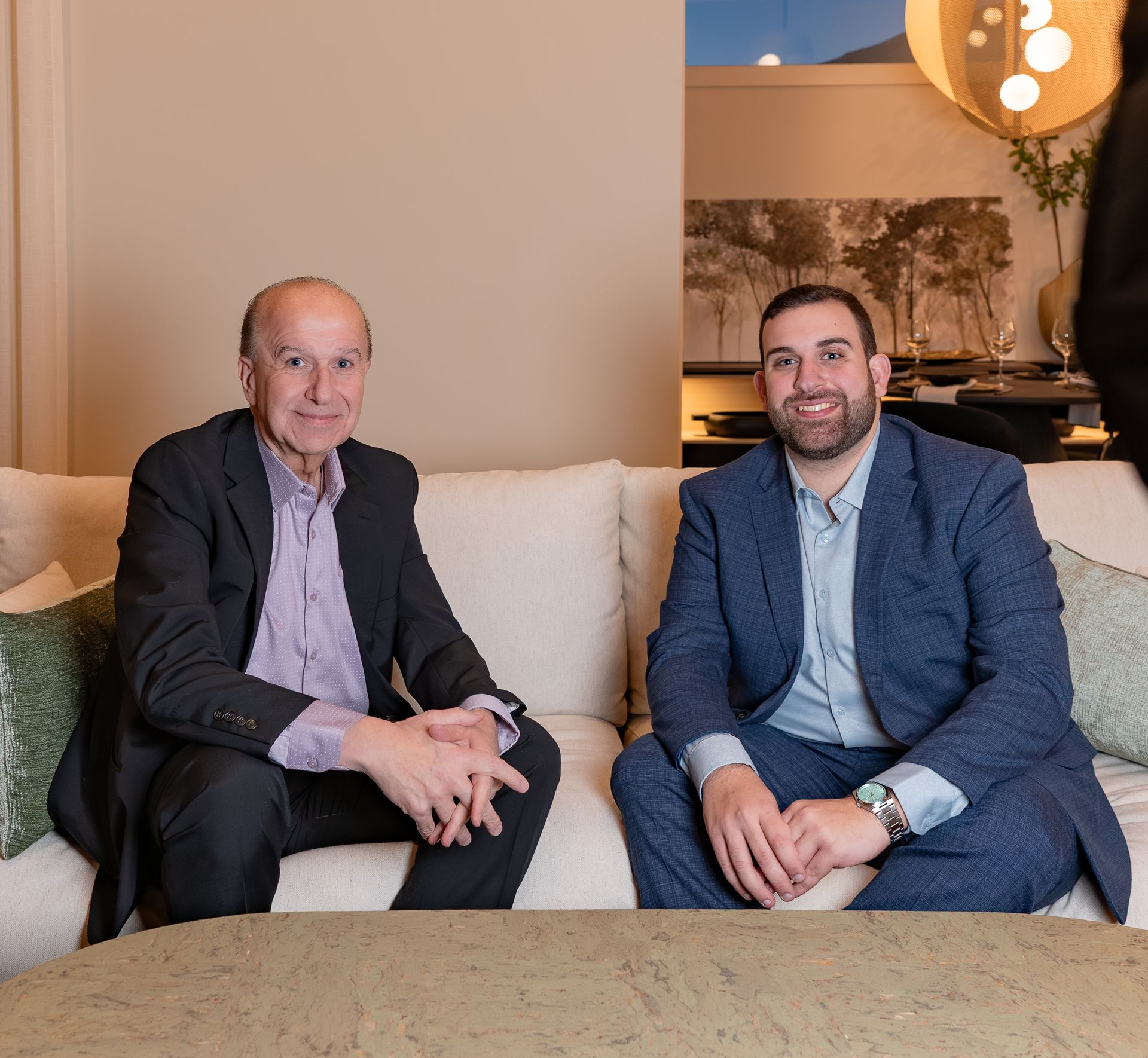 A bald man wearing a white sweater is smiling for the camera.