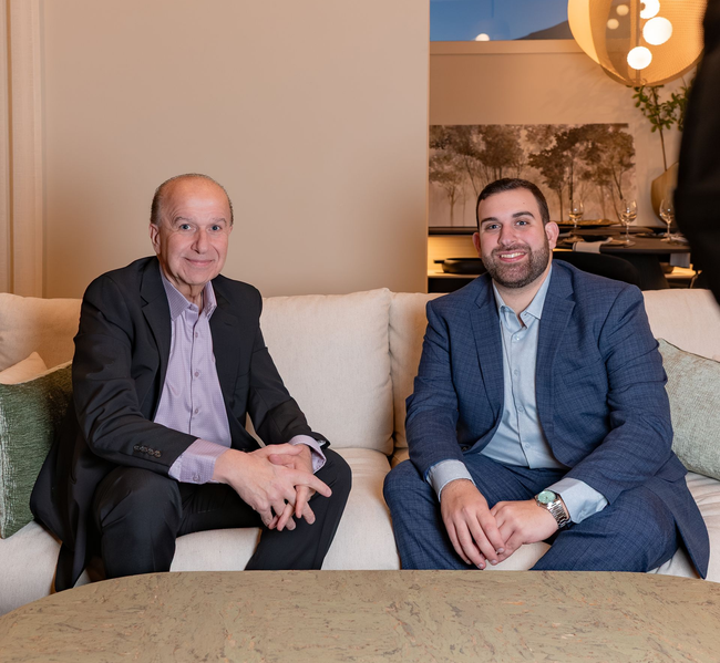 A bald man wearing a white sweater is smiling for the camera.