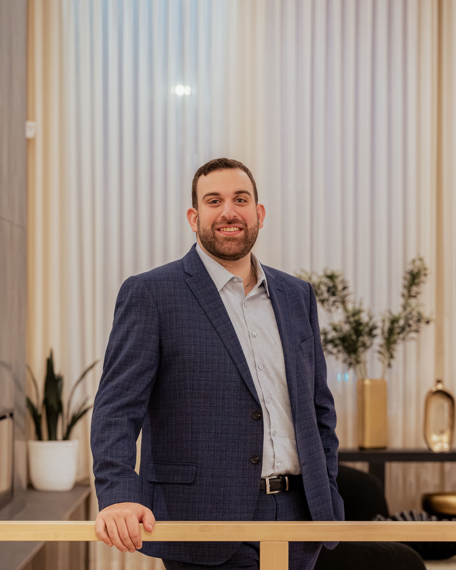 A bald man wearing a white sweater is smiling for the camera.