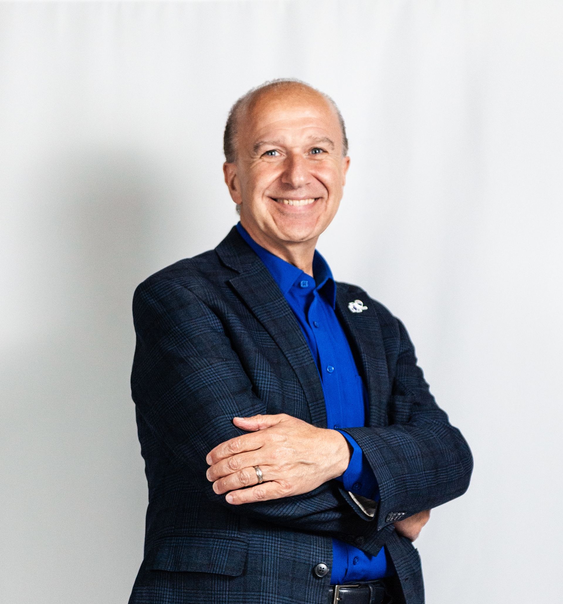 A man wearing a white sweater is smiling for the camera.