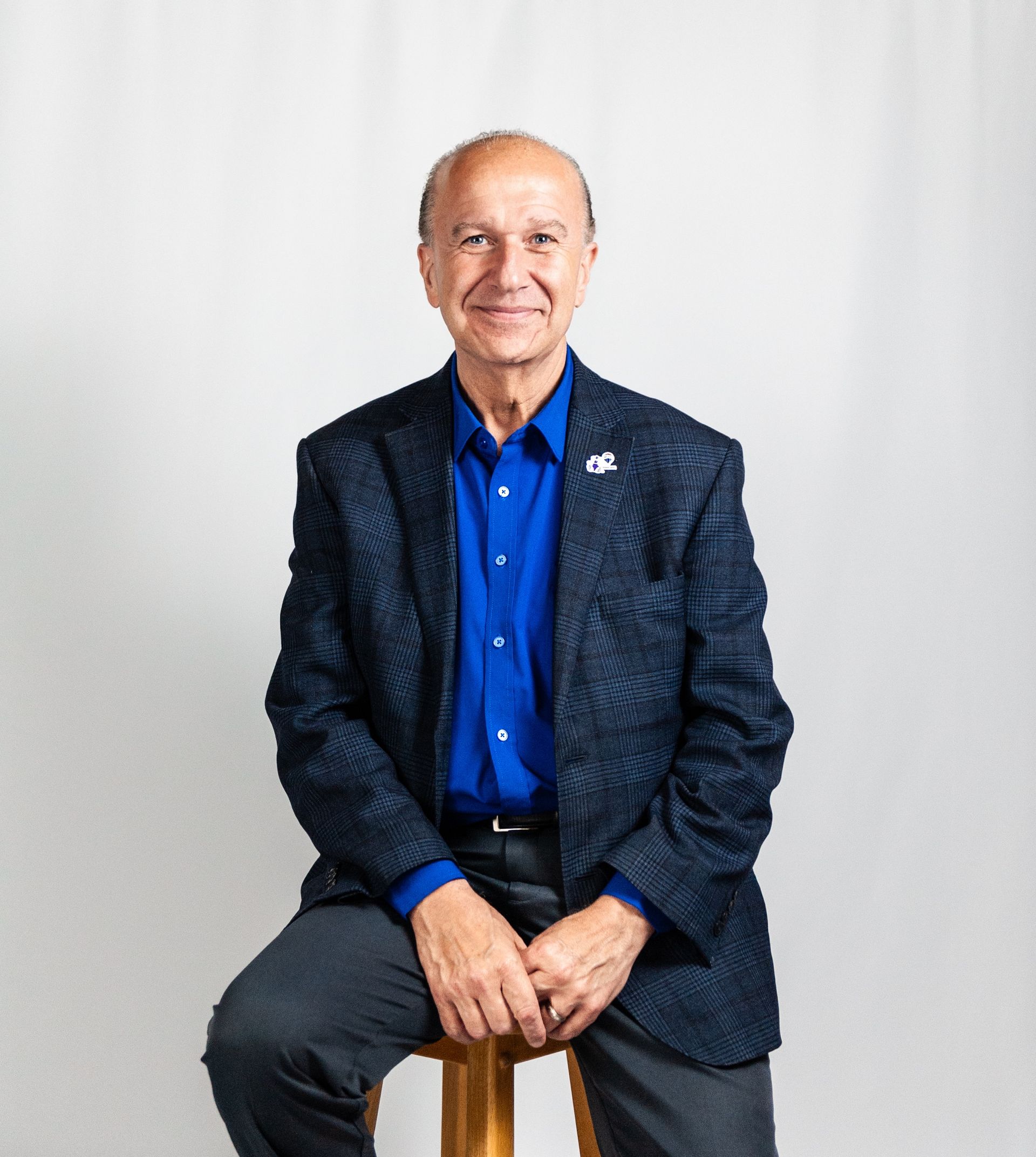 A bald man wearing a white sweater is smiling for the camera.