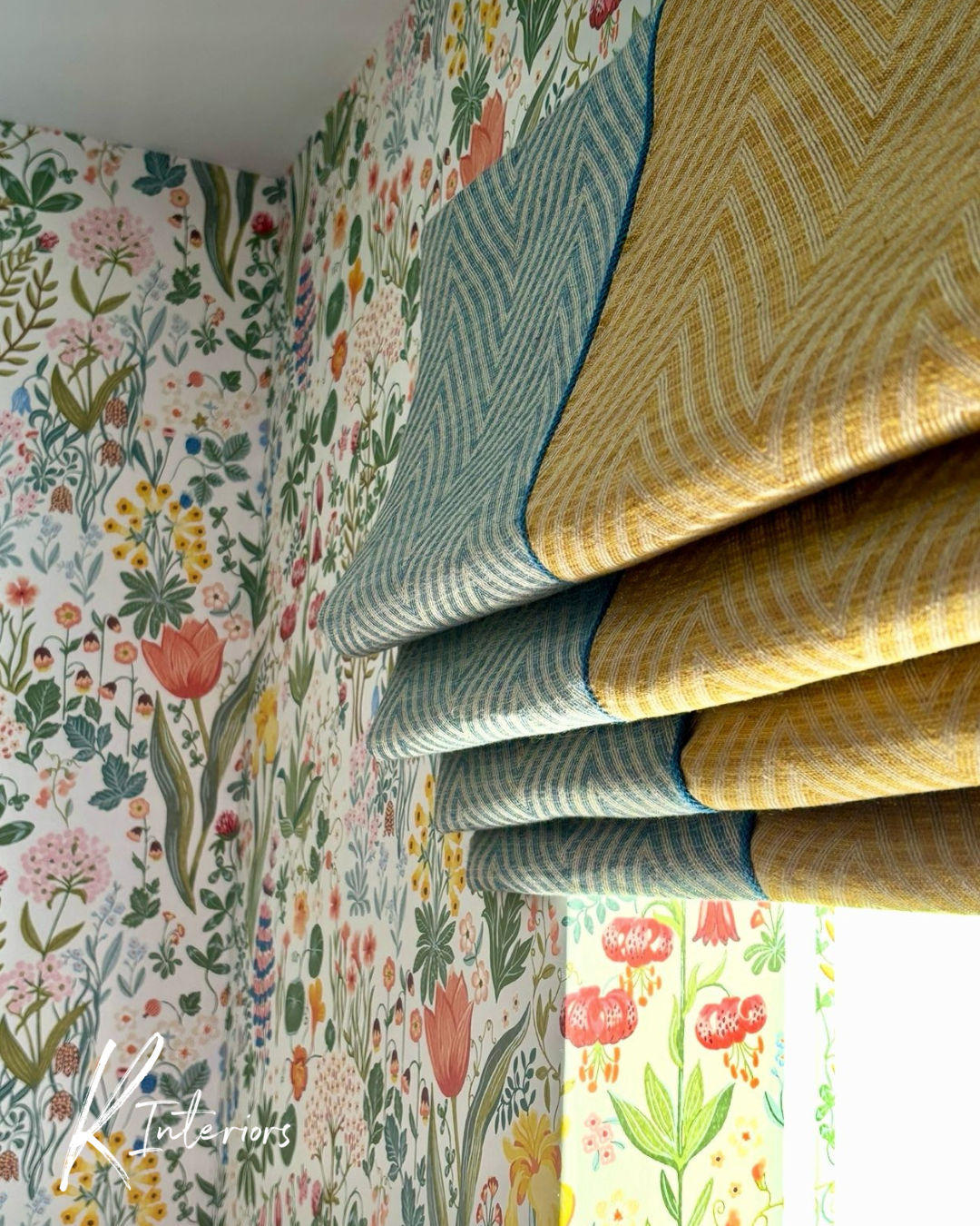 Roman blind in yellow and blue zigzag patterned fabric et against a small-print of colourful flowers on a white background. Designed by interior designer Kay James at K Interiors