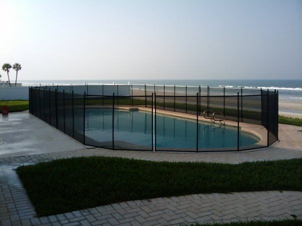 A swimming pool with a fence around it and a view of the ocean.