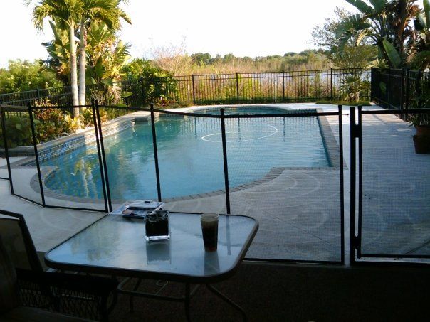 A fenced in pool with a table and chairs in front of it