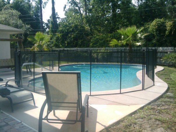 A pool with a fence around it and chairs around it