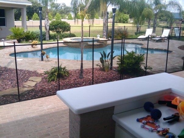 A fence surrounds a large swimming pool in a backyard