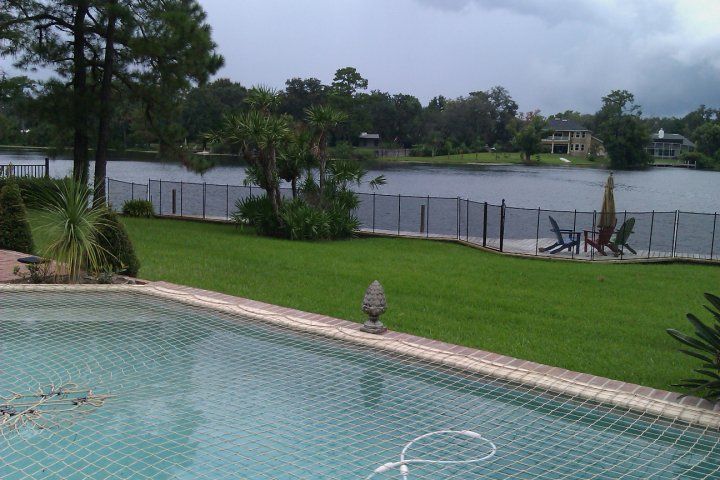 A fenced in swimming pool with a lake in the background