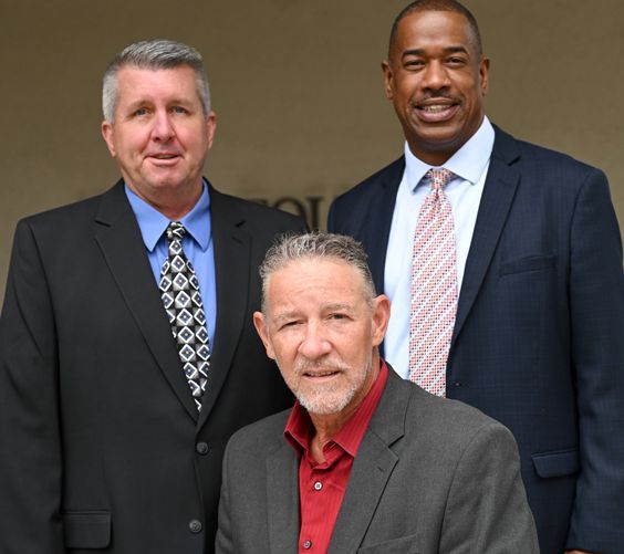 Three men in suits and ties are posing for a picture