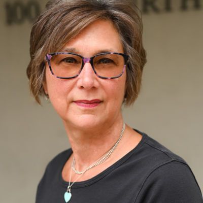 A woman wearing glasses and a necklace with a heart pendant