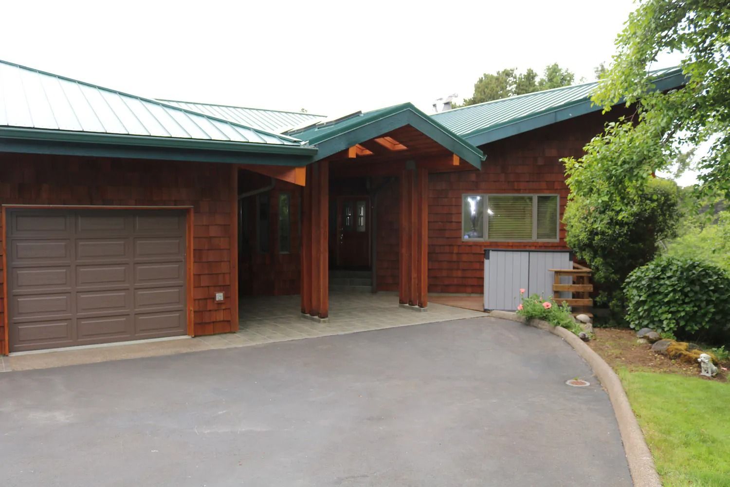 A large wooden house with a green roof and a driveway