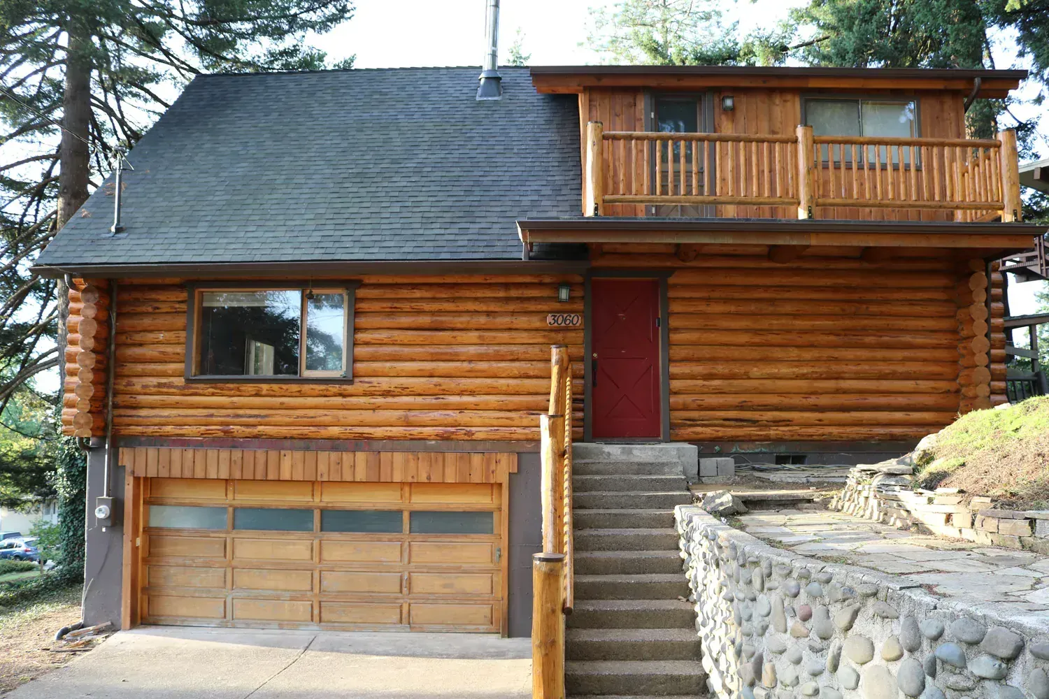 A log cabin with a garage and stairs leading up to it