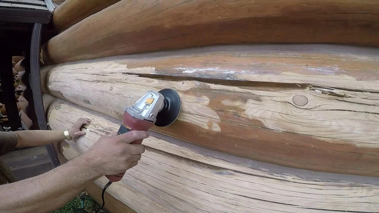 A person is using a grinder on a piece of wood.