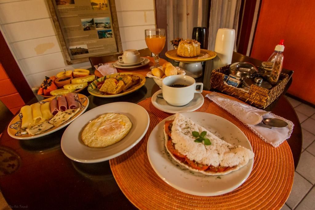 Café da manhã servido em uma mesa redonda, com diversos pratos, café e suco.