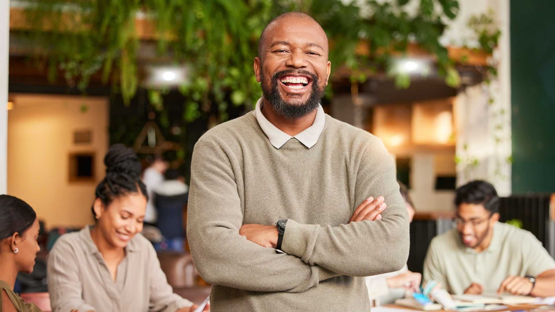A man with his arms crossed is standing in front of a group of people.