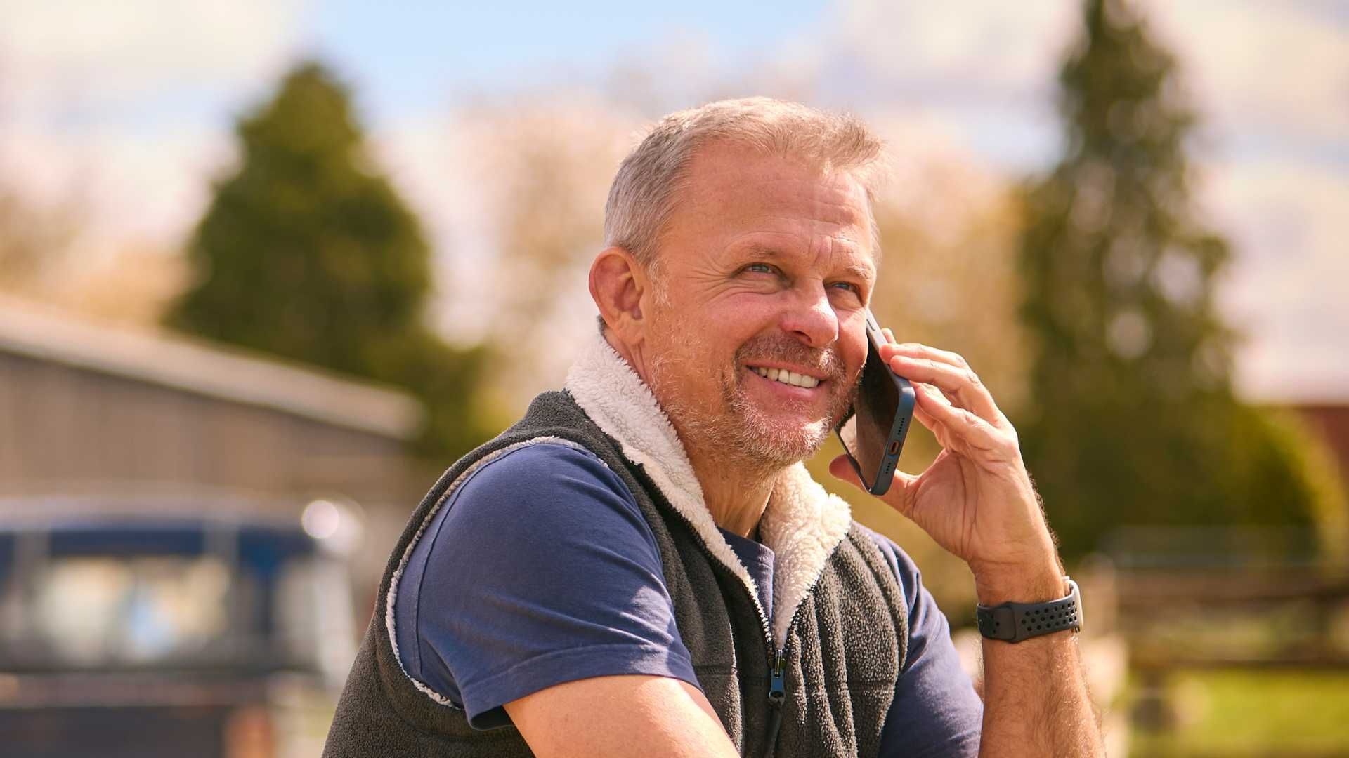A man with a towel around his neck is talking on a cell phone.