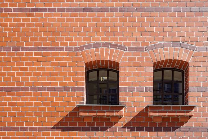 Brick wall with two arched windows and shadows