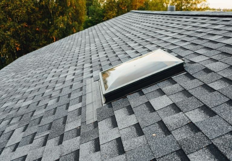 Person kneeling, using a torch to repair a roof.