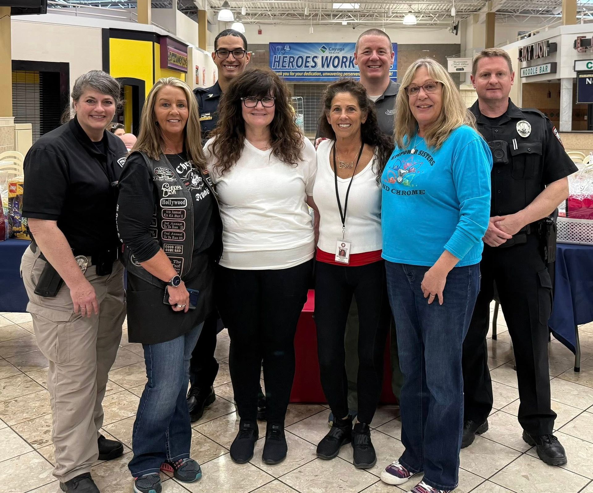 A group of people posing for a picture in front of a sign that says heroes