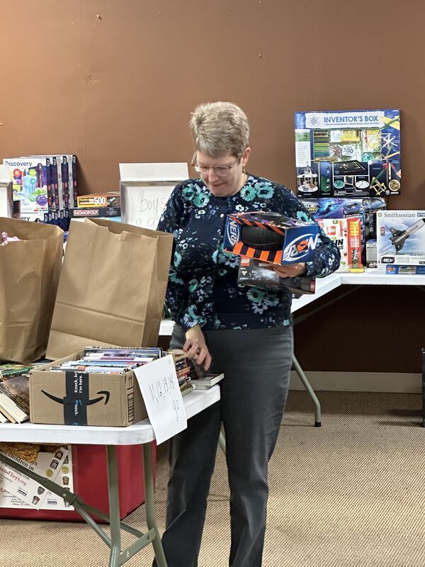 A woman is standing in front of a table full of toys.