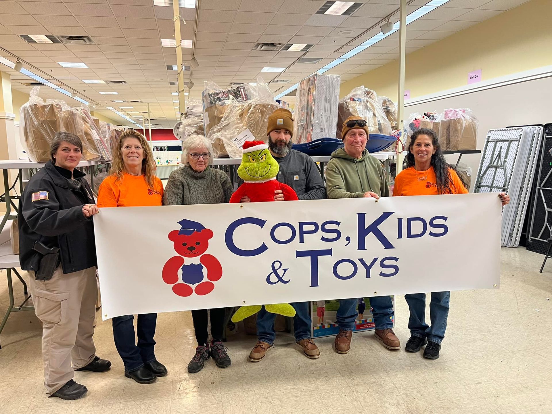 A group of people are holding a sign that says cops kids and toys.