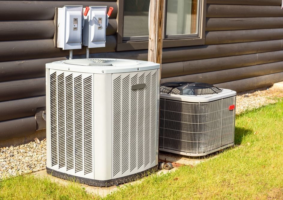 Two air conditioners are sitting on the side of a house.