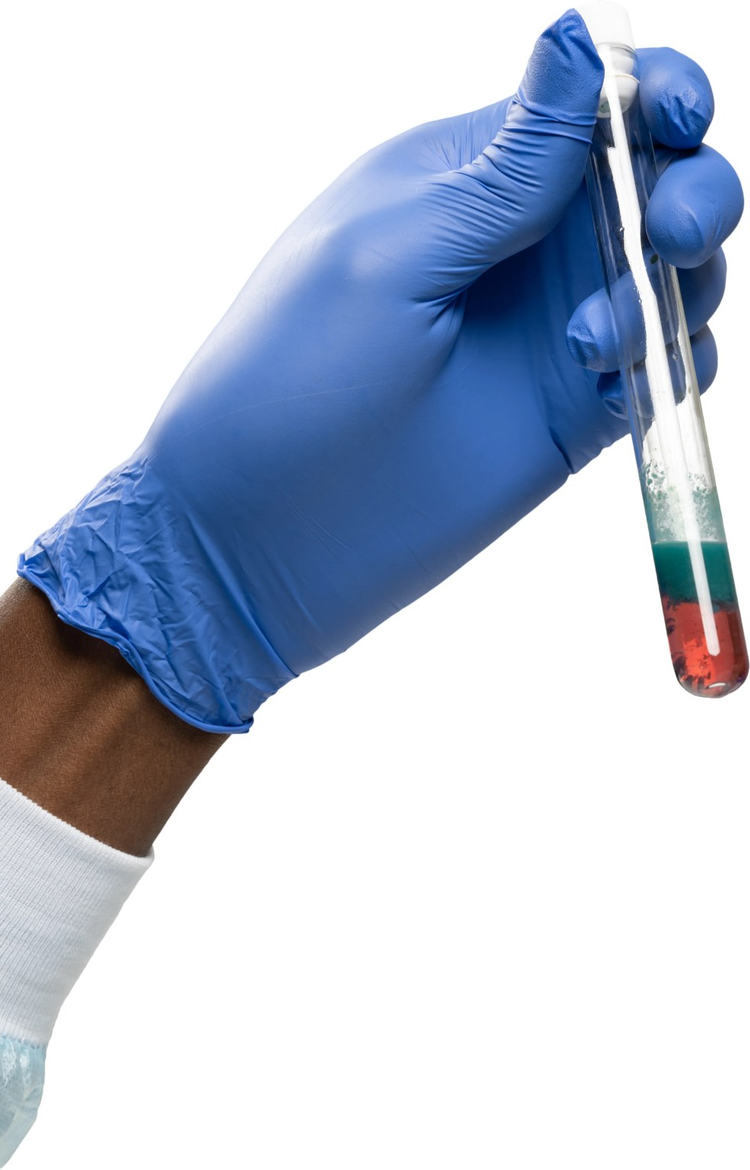 Hand in blue glove holding a test tube with layered red, green, and white liquids.