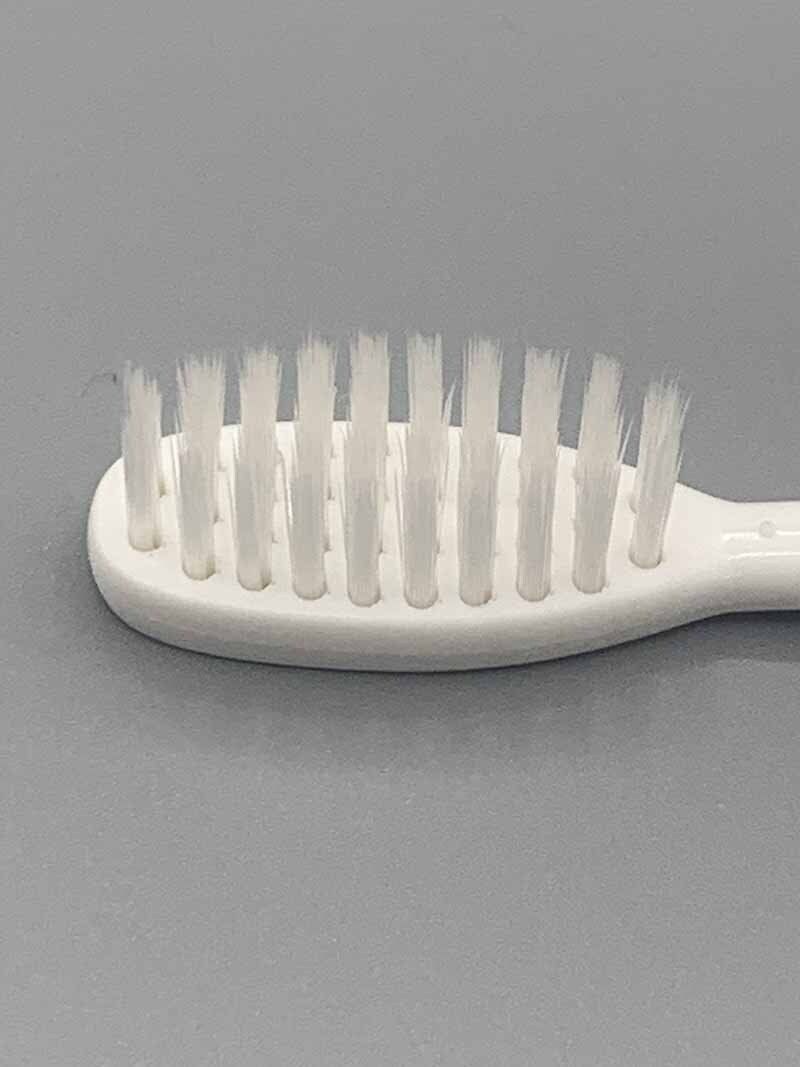 A close up of a white toothbrush on a gray surface.