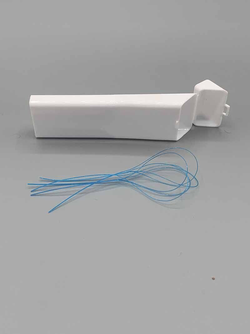 A white object with a blue string attached to it is sitting on a gray surface.