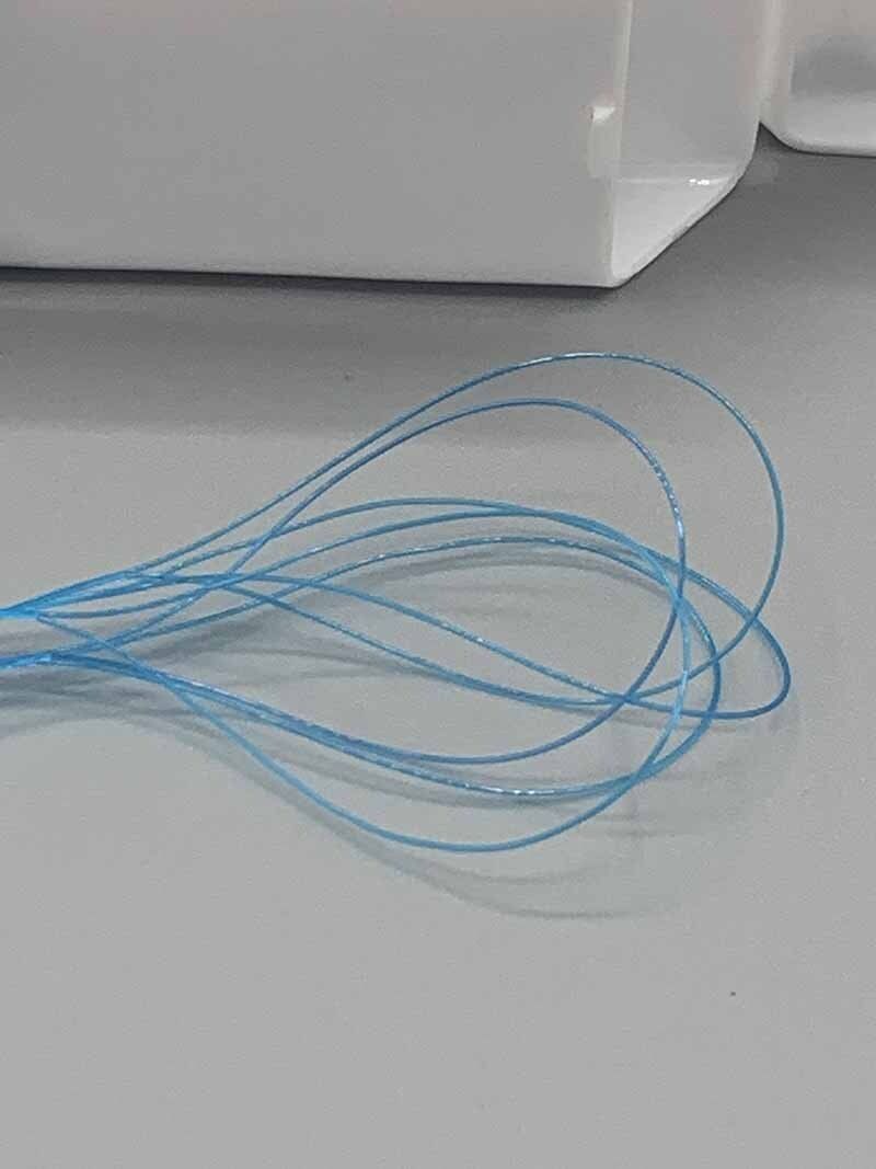 A blue string is sitting on a table next to a white box.